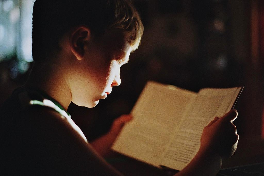 Open book and laptop on wooden desk illustrating study and guidance